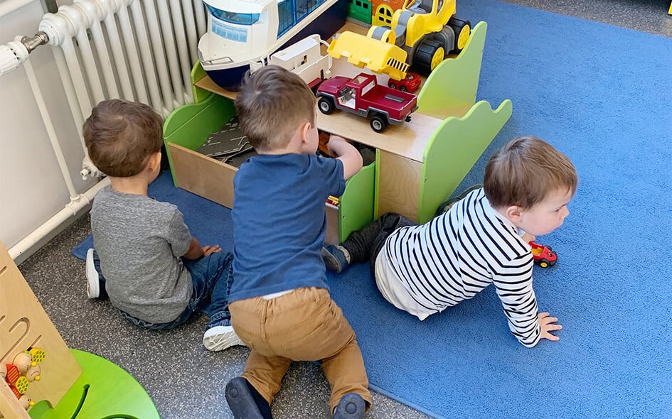Drei Kinder spielen am Boden.