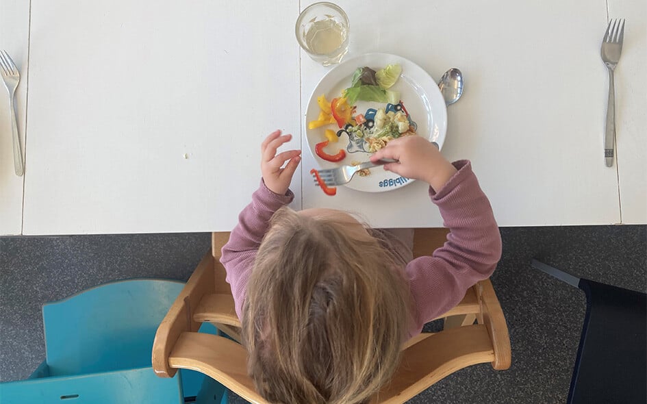 Ein Kind sitzt an einem Tisch und isst.