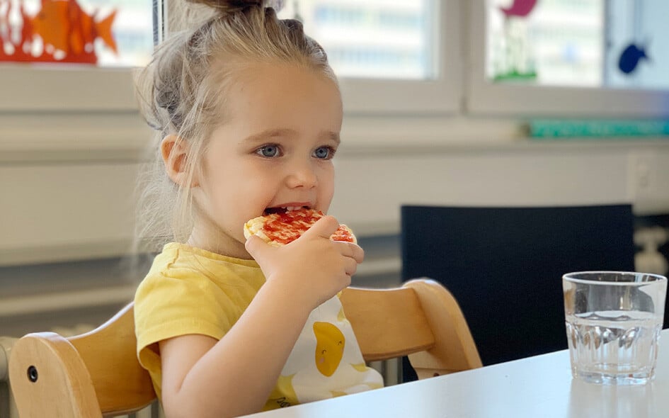 Ein Kind isst ein Brotschnitte.