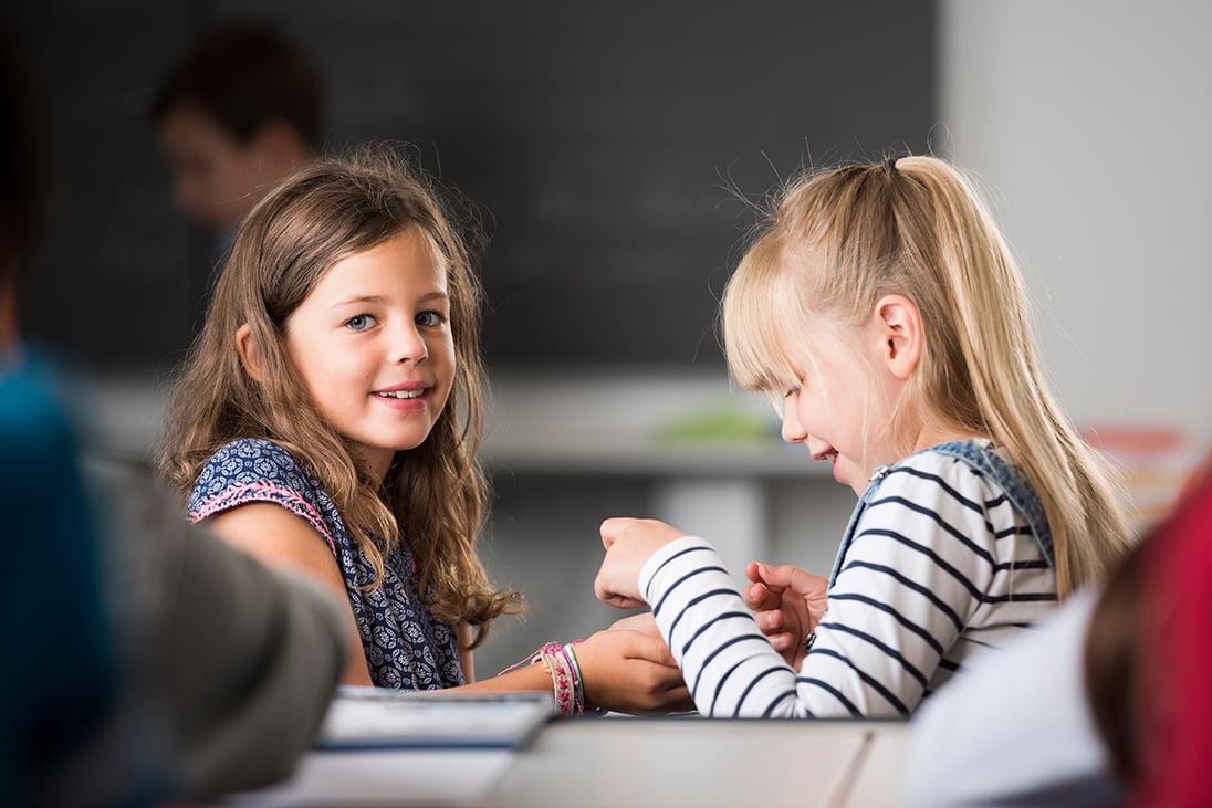 Zwei Mädchen sitzen sich gegenüber.