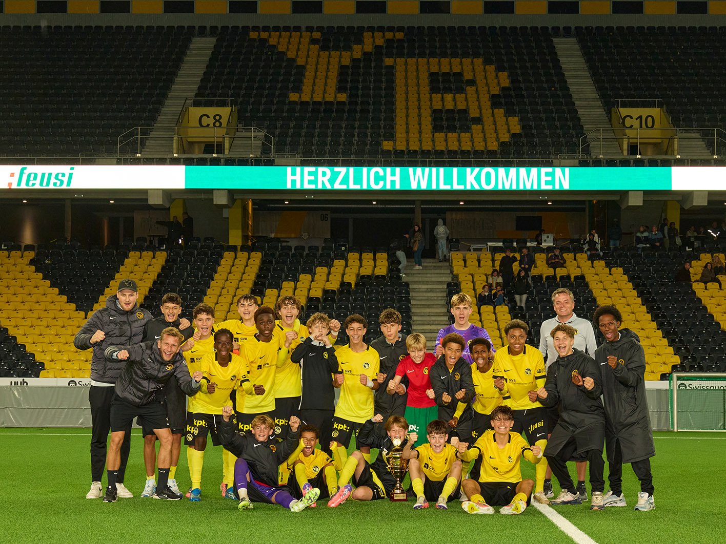 YB-Nachwuchsmannschaft posiert mit Trainern und Siegerpokal für ein Gruppenfoto im Stadion.