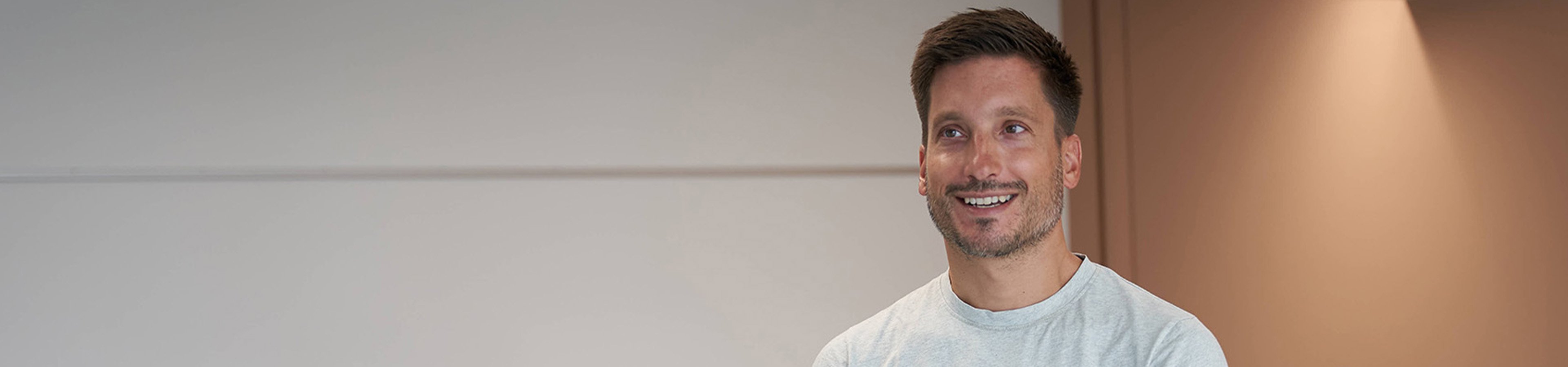 Im Vordergrund ein Mann. Im Hintergrund sitzen einige Schülerinnen und Schüler.