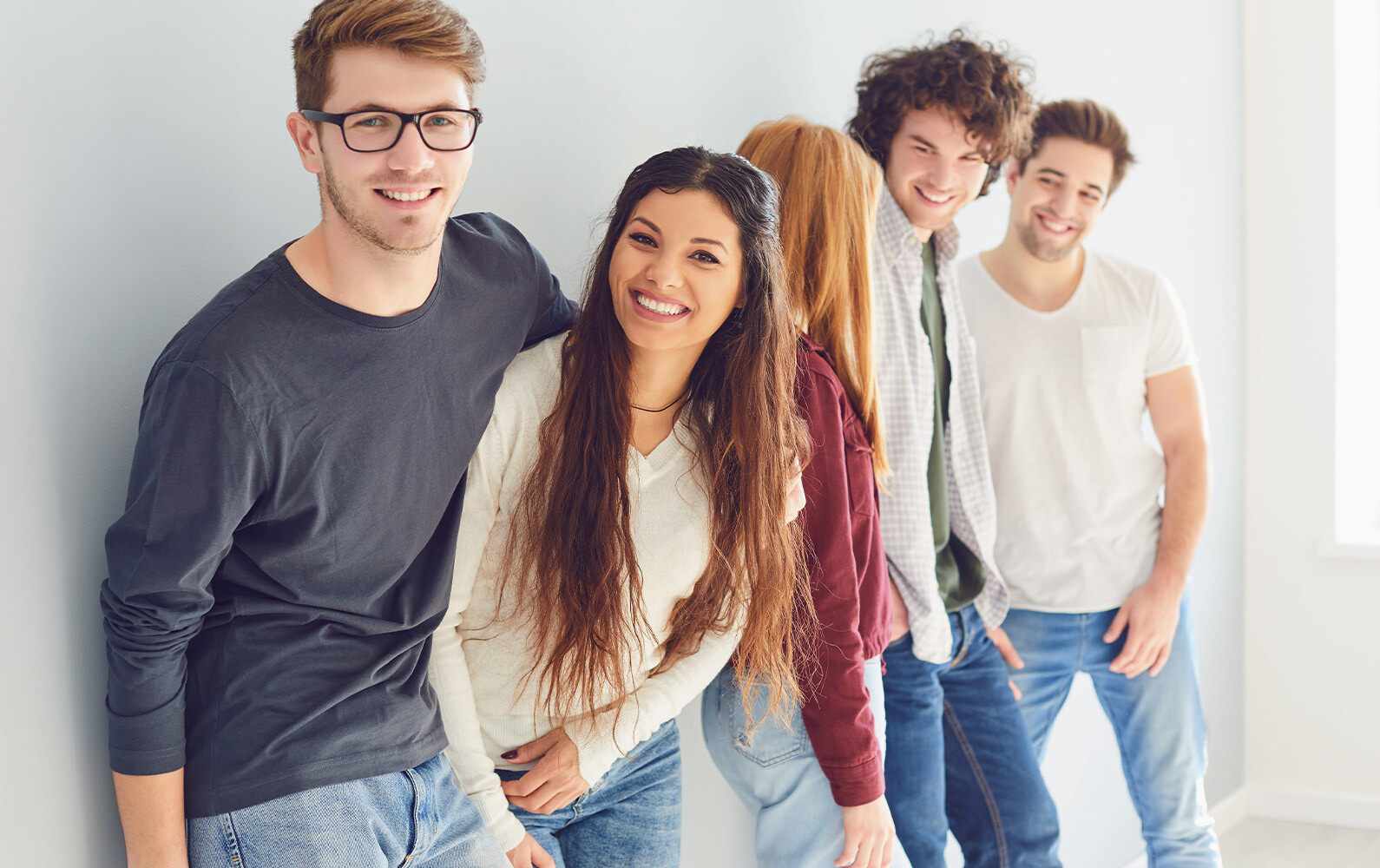 Fünf Personen lehnen sich an eine Wand.