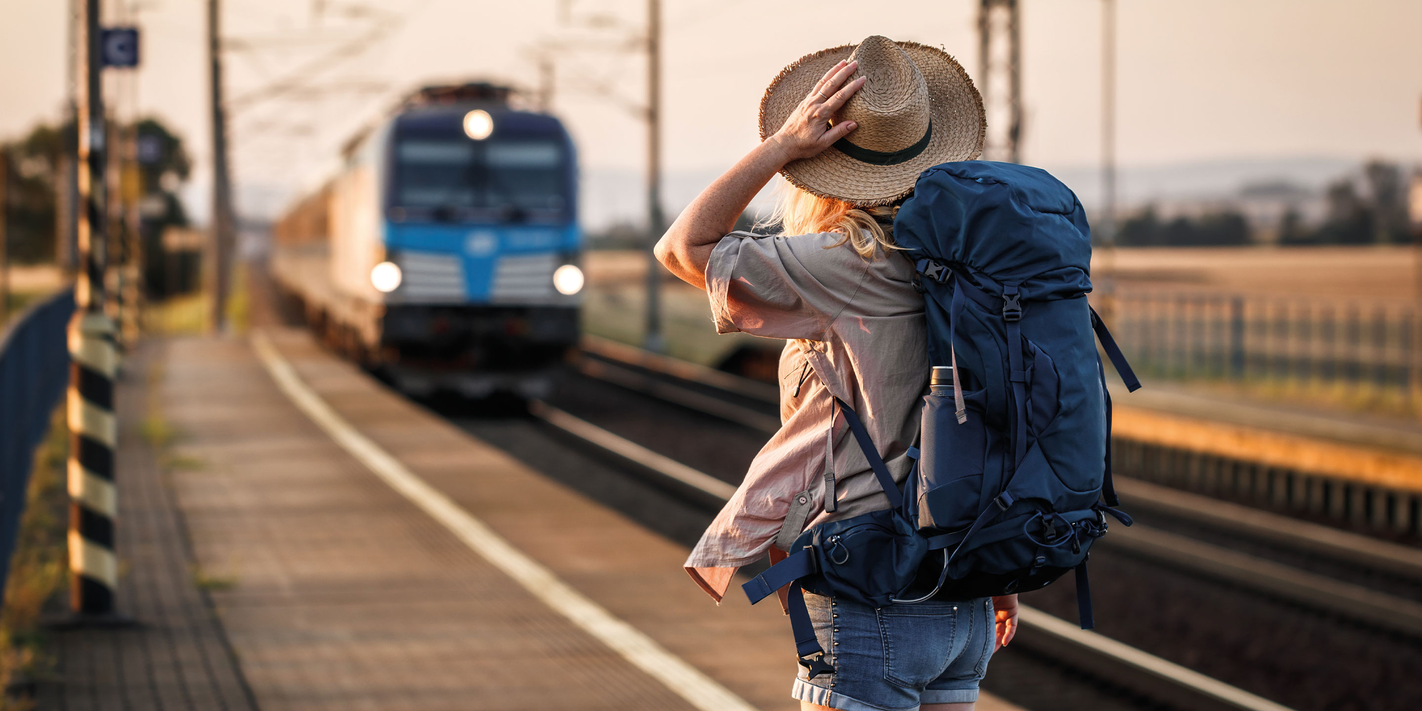 Eine Person steht auf einem Perron. Ein Zug fährt ein.