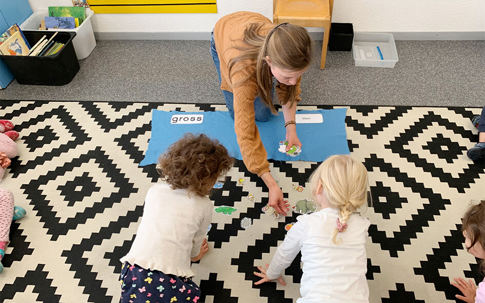 Ein Frau mit Kindern spielen zusammen am Boden.