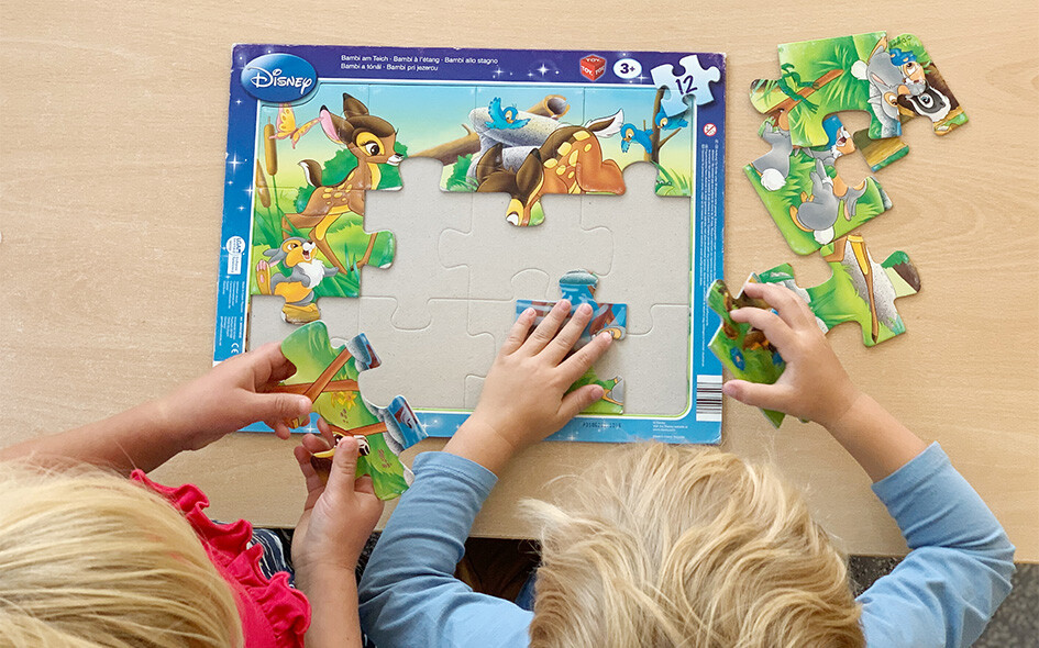 Zwei Kinder spielen ein Puzzle.