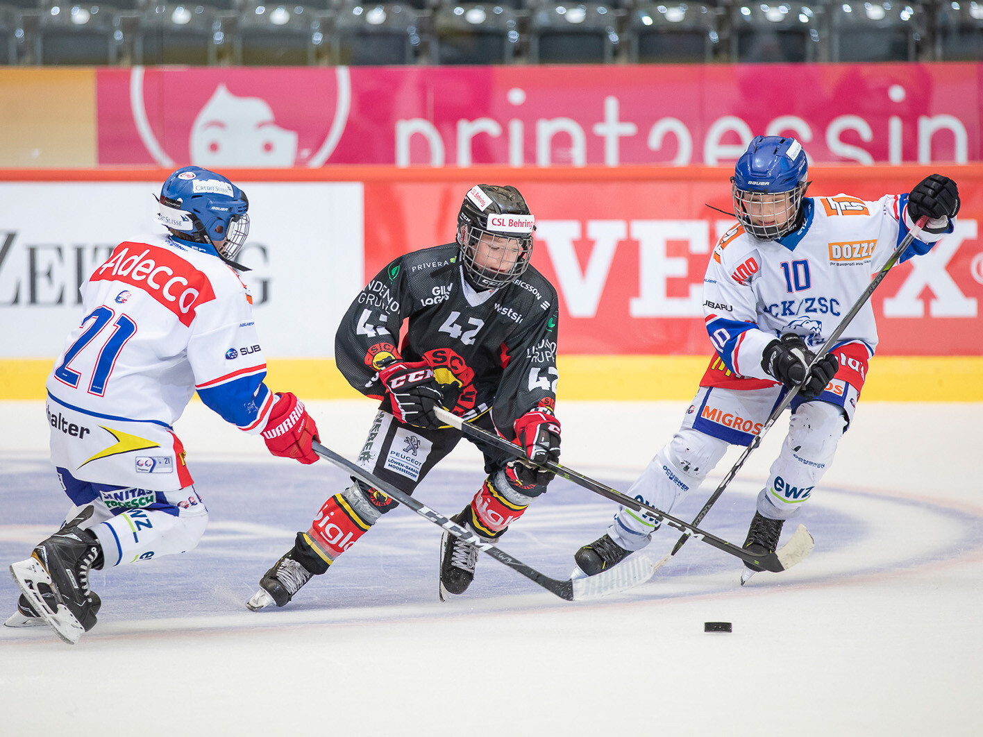 Drei Eishockeyspieler kämpfen um den Puck.