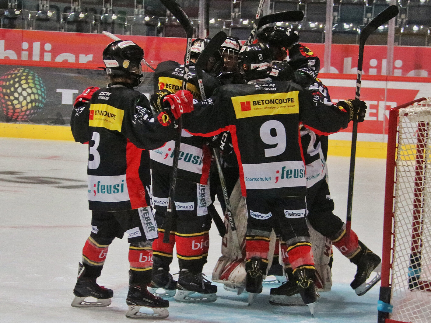 Mehrere SCB Future Eishockeyspieler versammeln sich vor dem Eishockey-Tor.