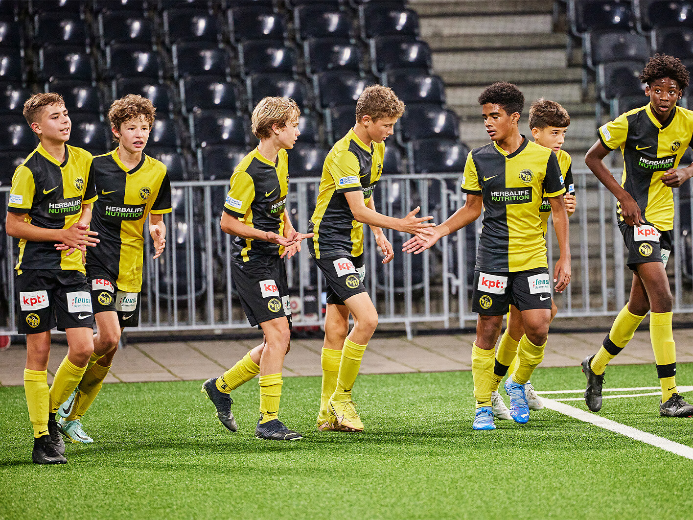 Verschiedene Spieler in gelb-schwarzen Trikots laufen auf das Fussballfeld.