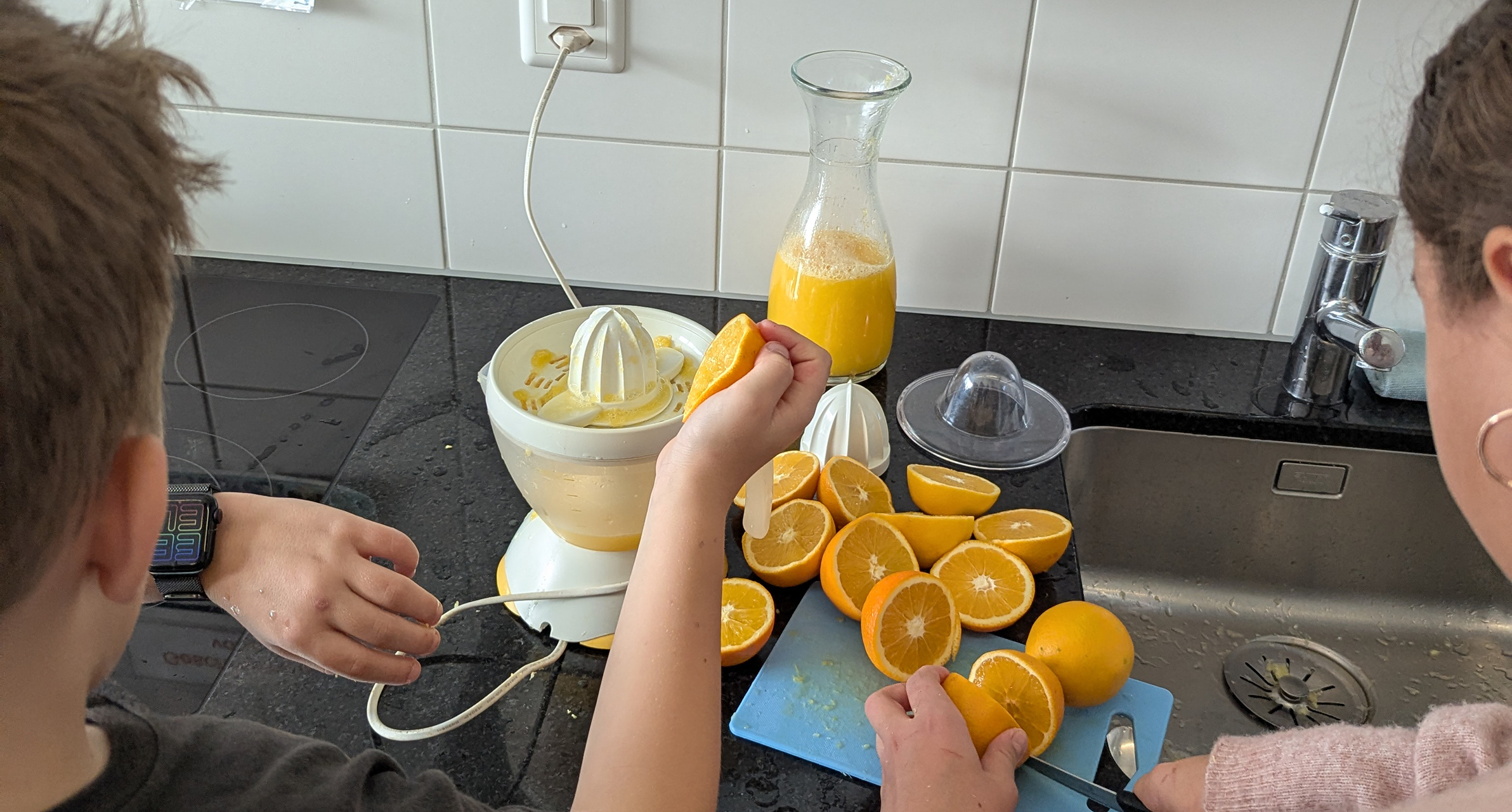 Zwei Schüler schneiden Orangen und machen Saft in einer Saftmaschine.