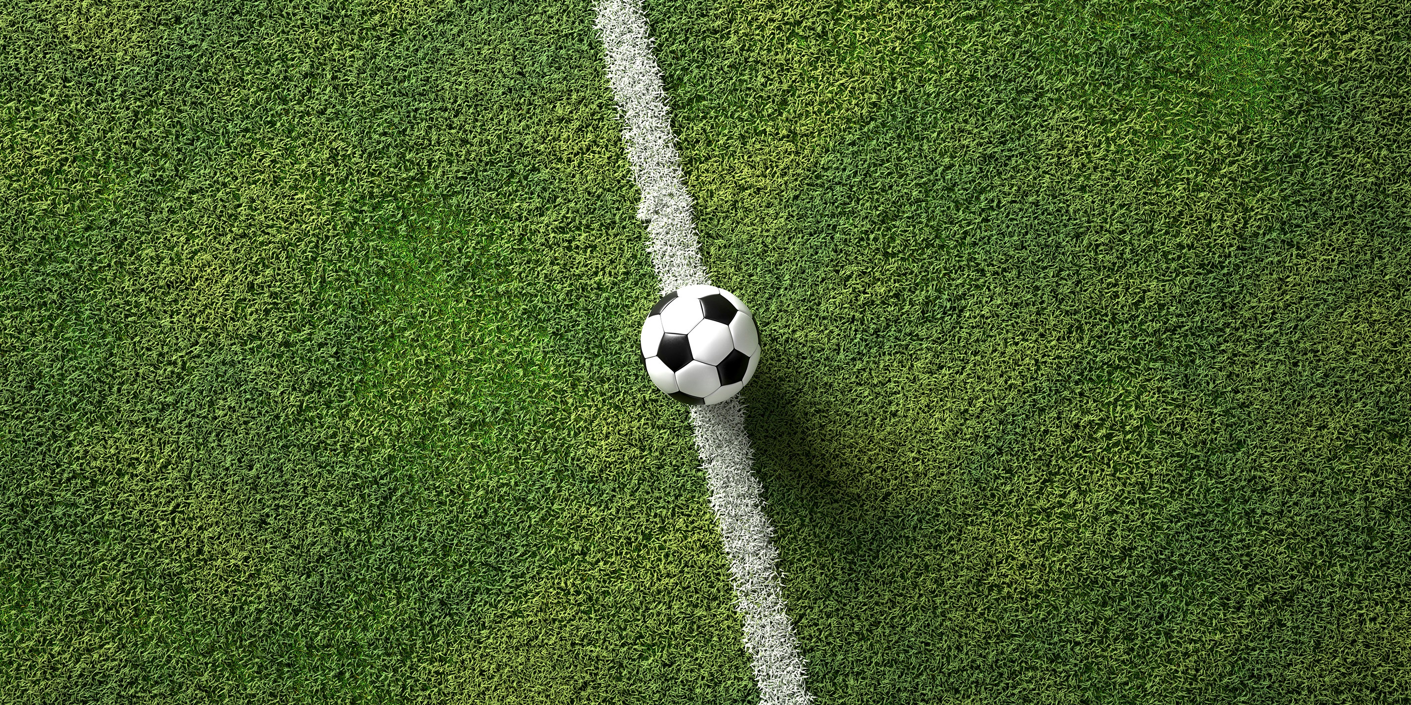 Ein Fussball liegt auf der Mittellinie eines grünen Spielfelds und symbolisiert den Anpfiff oder Spielbeginn.