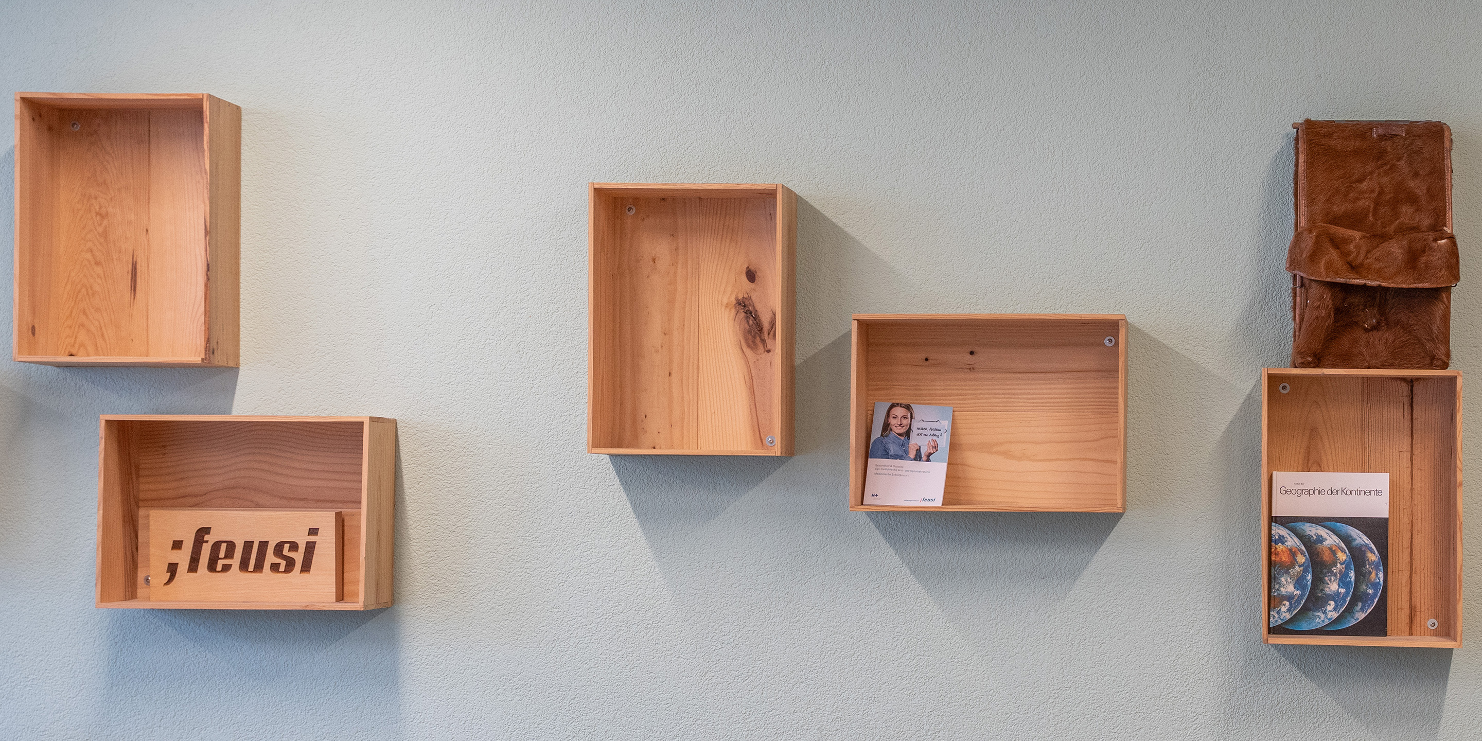 An einer Wand hangen verschiedene Holzkasten.