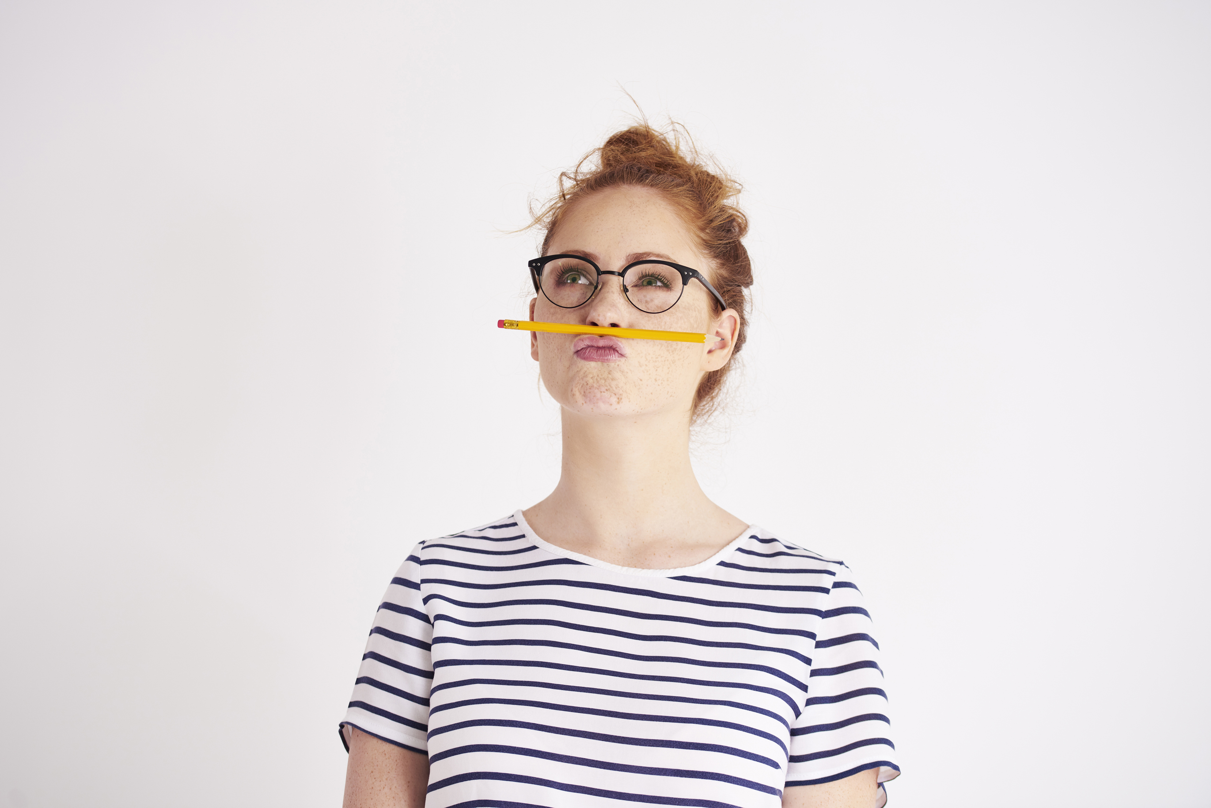 Eine Frau hat einen Stift zwischen Mund und Nase eingeklemmt.
