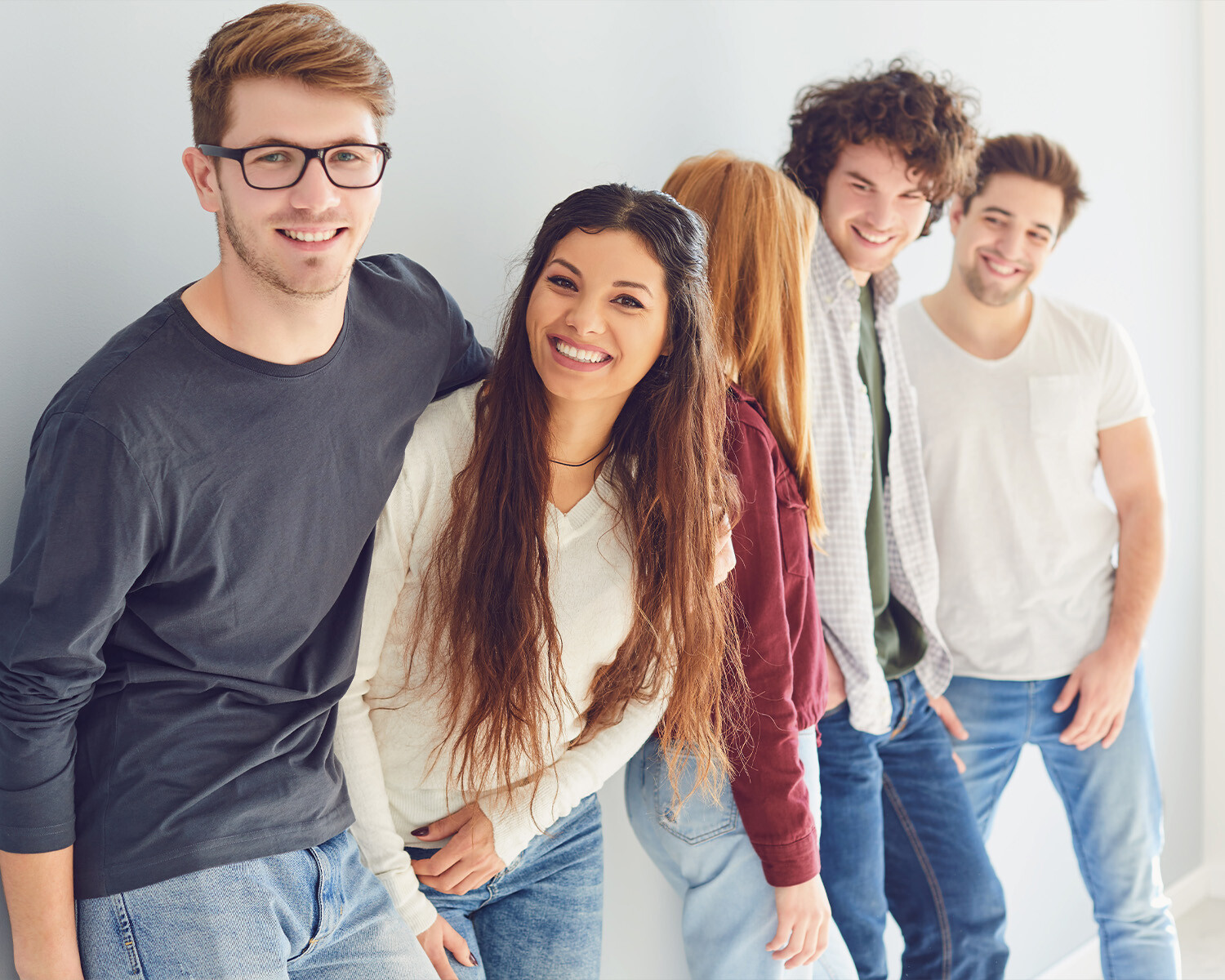 Eine Gruppe mit fünf Personen lehnen sich an eine Wand.
