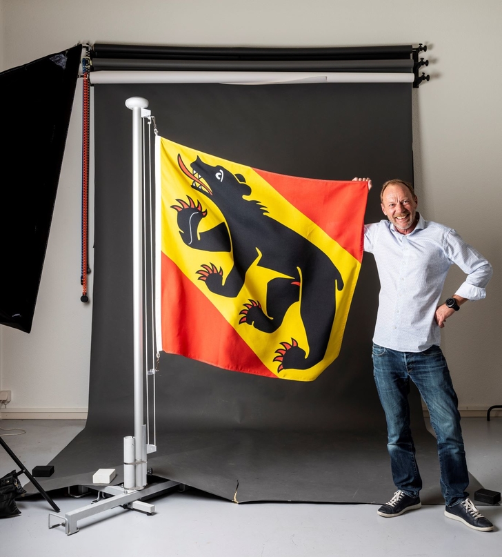 Der Feusi-Dozent Markus Hotz steht neben einer grossen Fahne mit dem Berner Wappen