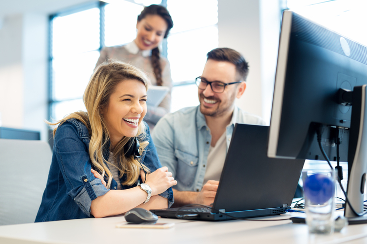 Eine Frau und ein Mann arbeiten zusammen am Laptop und PC.