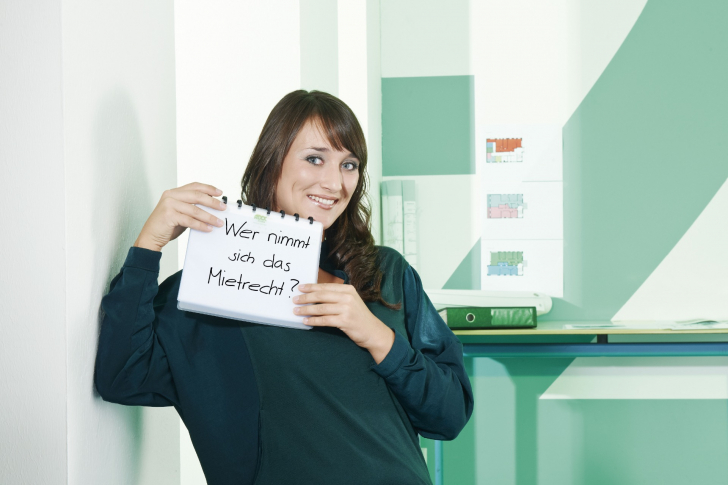 Junge Frau hält ein Schild hoch mit der Aufschrift: Wer nimmt sich das Mietrecht?