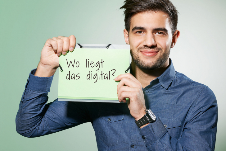 Mann hält Schild mit den Worten: Wo liegt das digital?