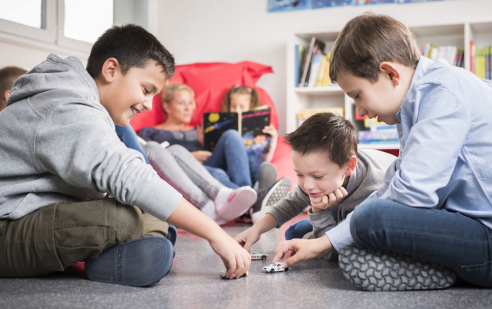 Schülerinnen und Schüler sitzen zusammen und spielen gemeinsam