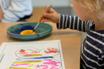 Ein Kind malt einen Schmetterling farbig aus.